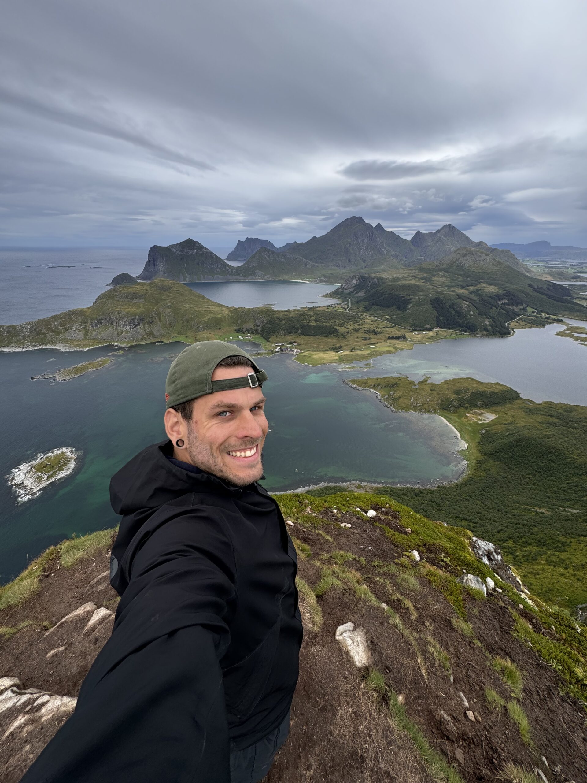 Alex l&auml;chelt in die Kamera, im Hintergrund die Berge und Fjorde der Lofoten