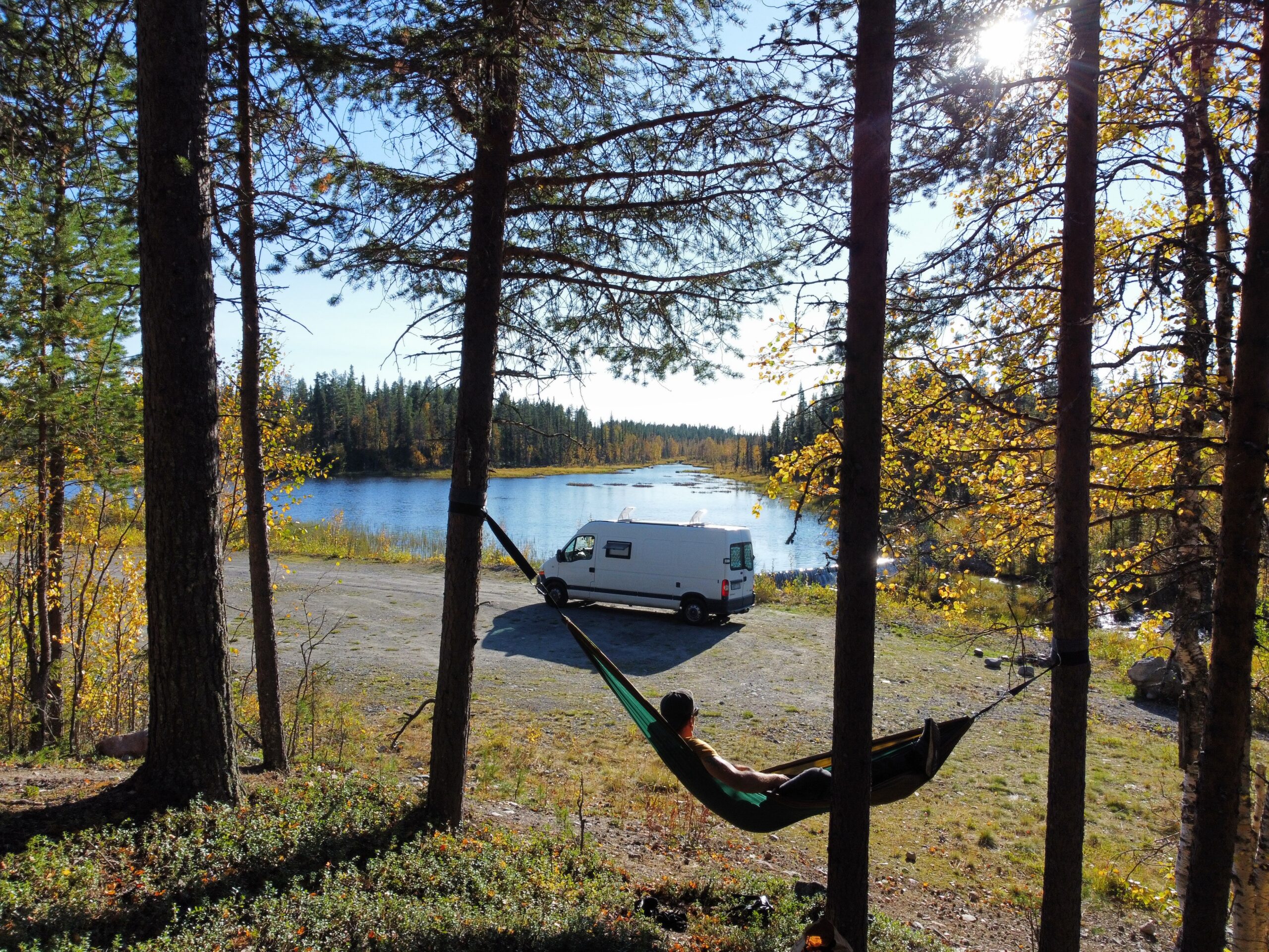 Camper-Van am See im Herbstwald, im Vordergrund Alex in der H&auml;ngematte